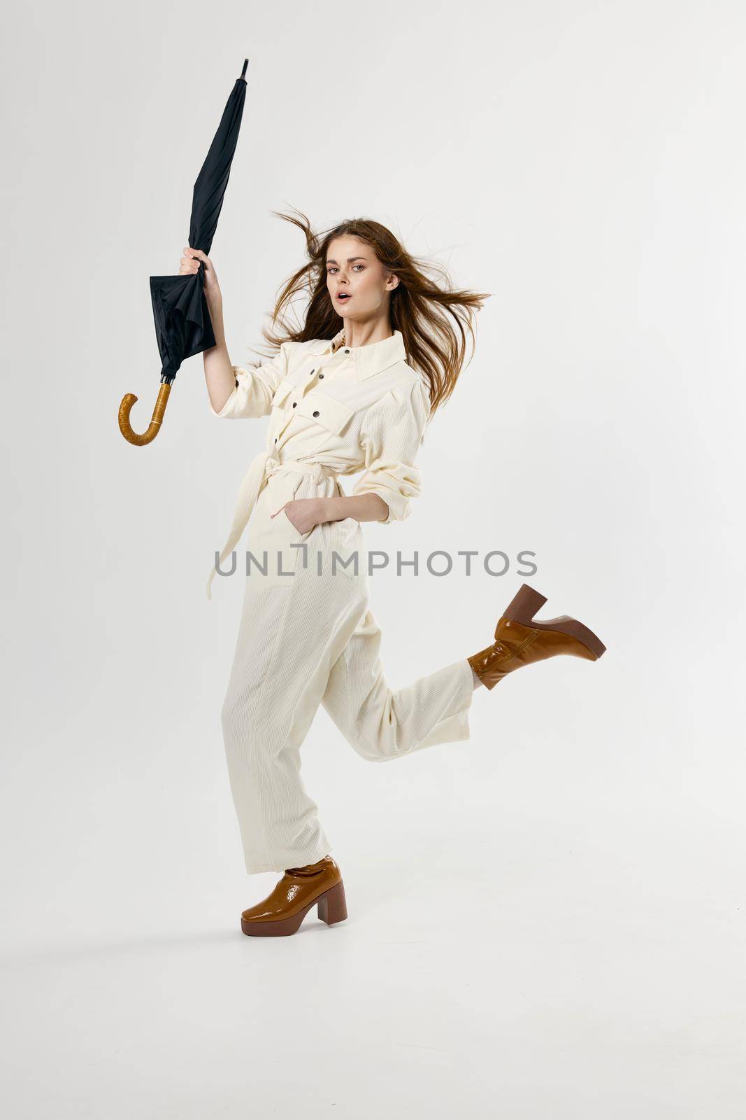 woman in white jumpsuit umbrella in hands studio. High quality photo