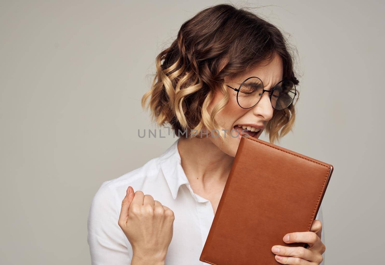 Smart woman with a notebook in her hands and in a white shirt on a gray background cropped view. High quality photo