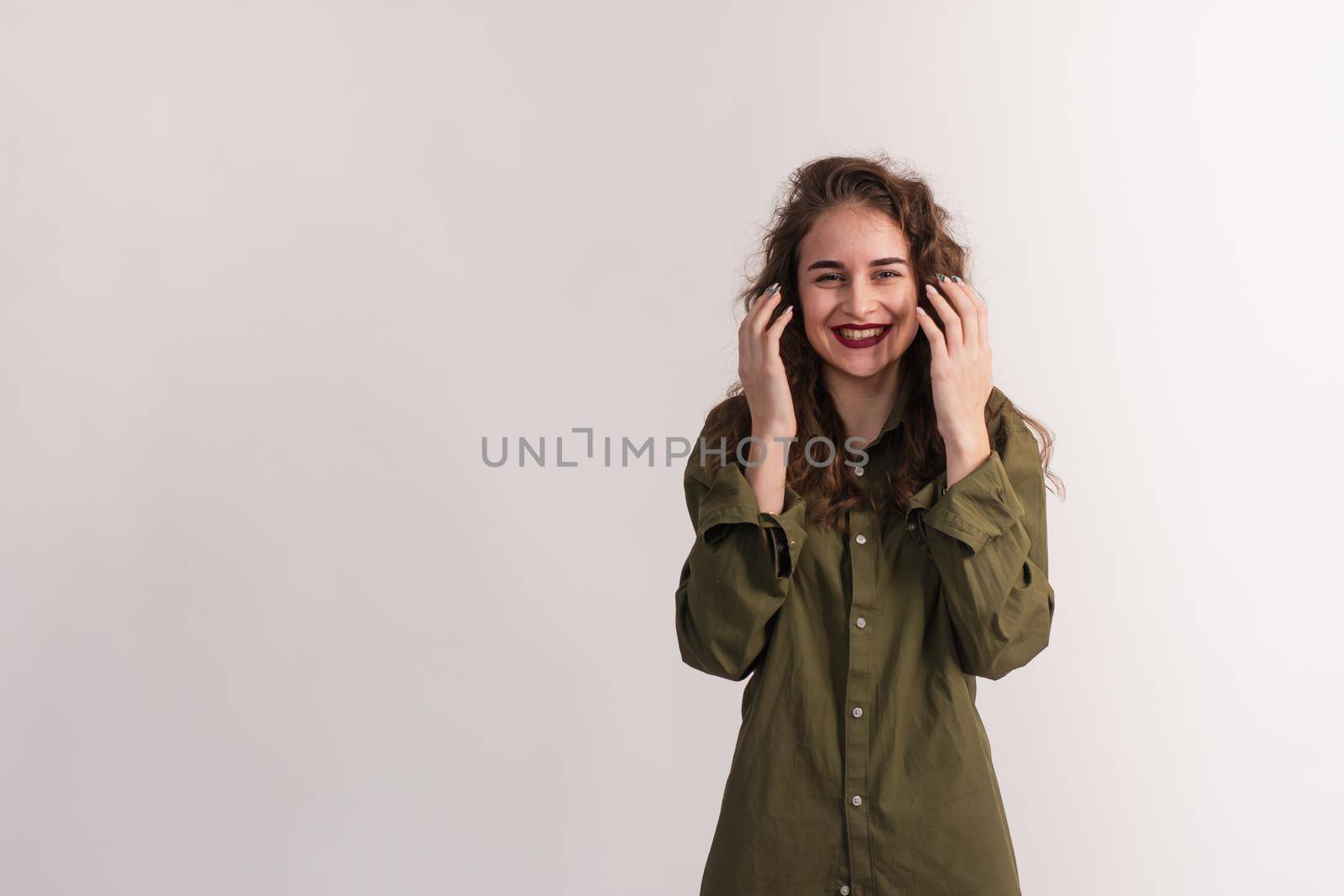 A surprised, smiling girl holds her hands near her face. The young woman is happy and does not believe that this happened. isolated on a white background. copy space