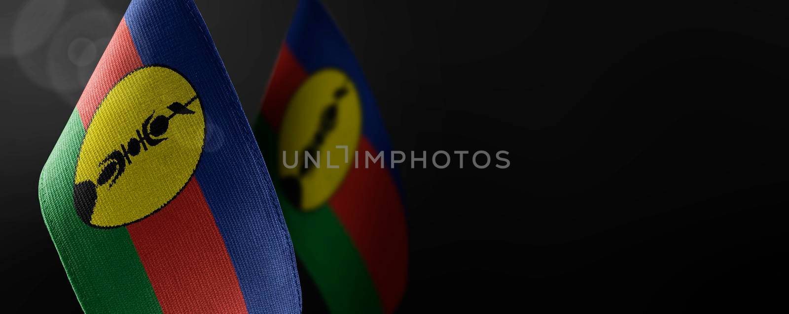 Small national flags of the New Caledonia on a dark background.