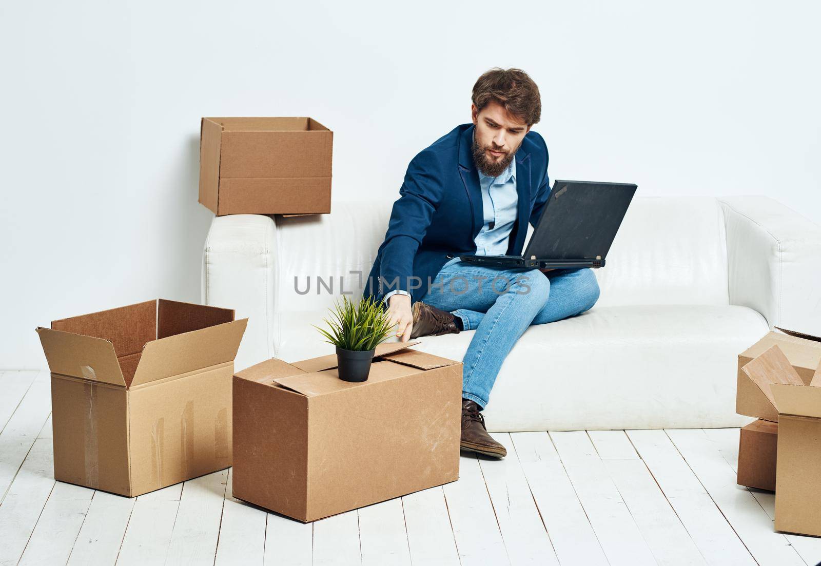 Business man sitting on the couch with laptop boxes with things unpacking office official. High quality photo