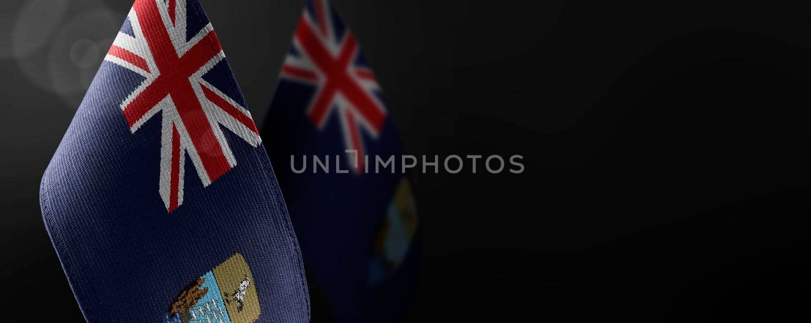 Small national flags of the Saint Helena on a dark background.