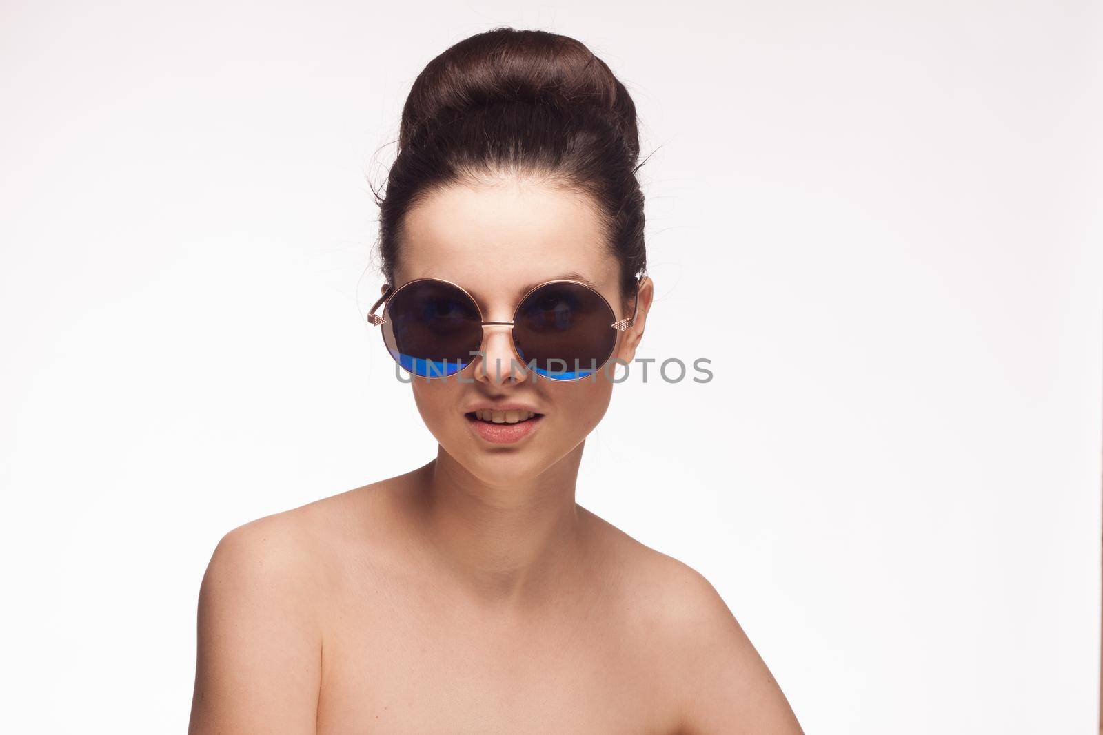 pretty woman naked shoulders and sunglasses light background fashion. High quality photo