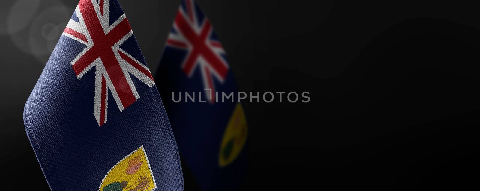 Small national flags of the Turks and Caicos Islands on a dark background.