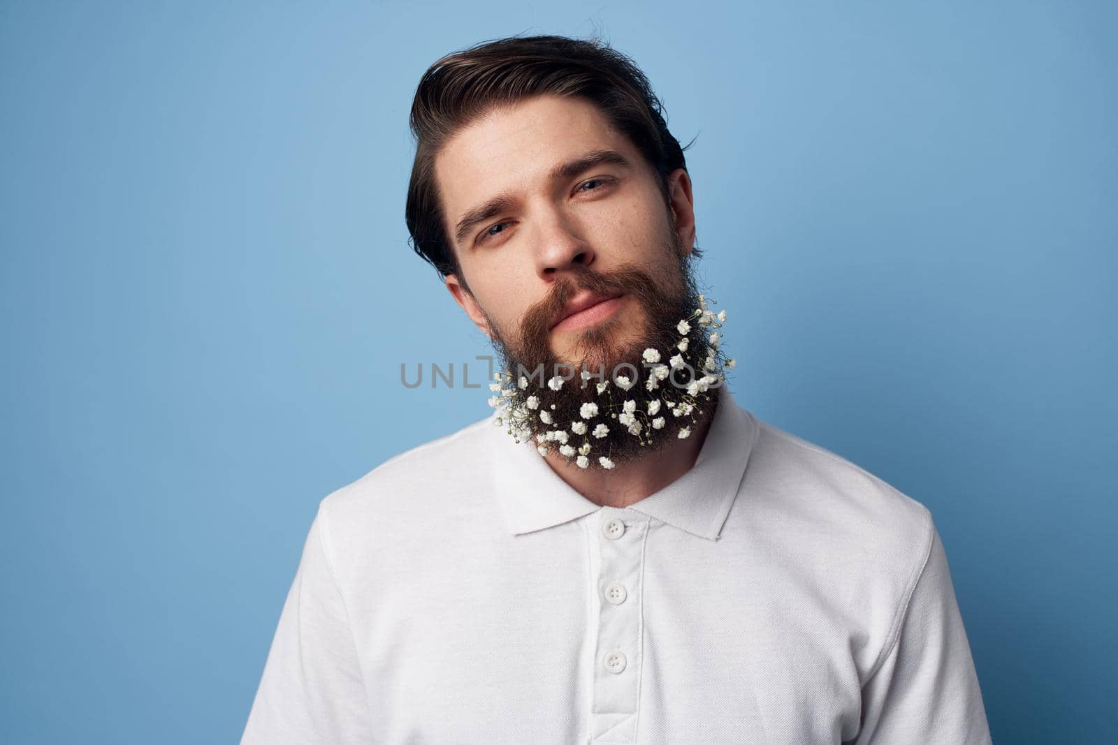 cute man flowers in beard t-shirt emotions blue background. High quality photo