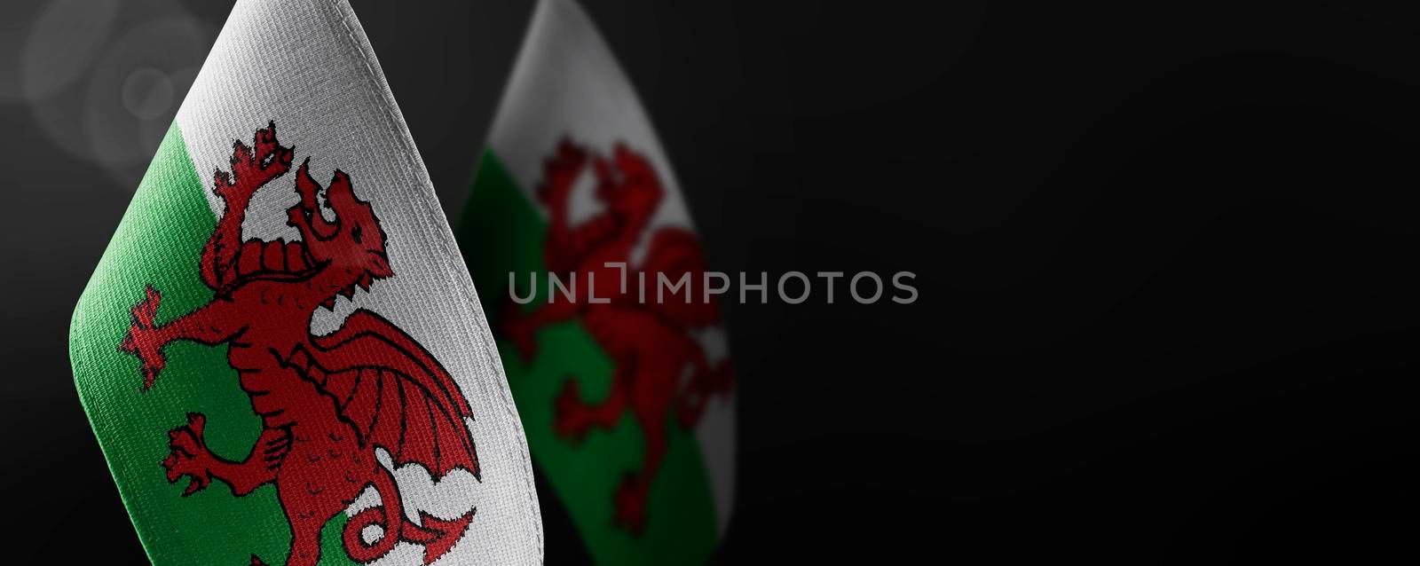 Small national flags of the Wales on a dark background.