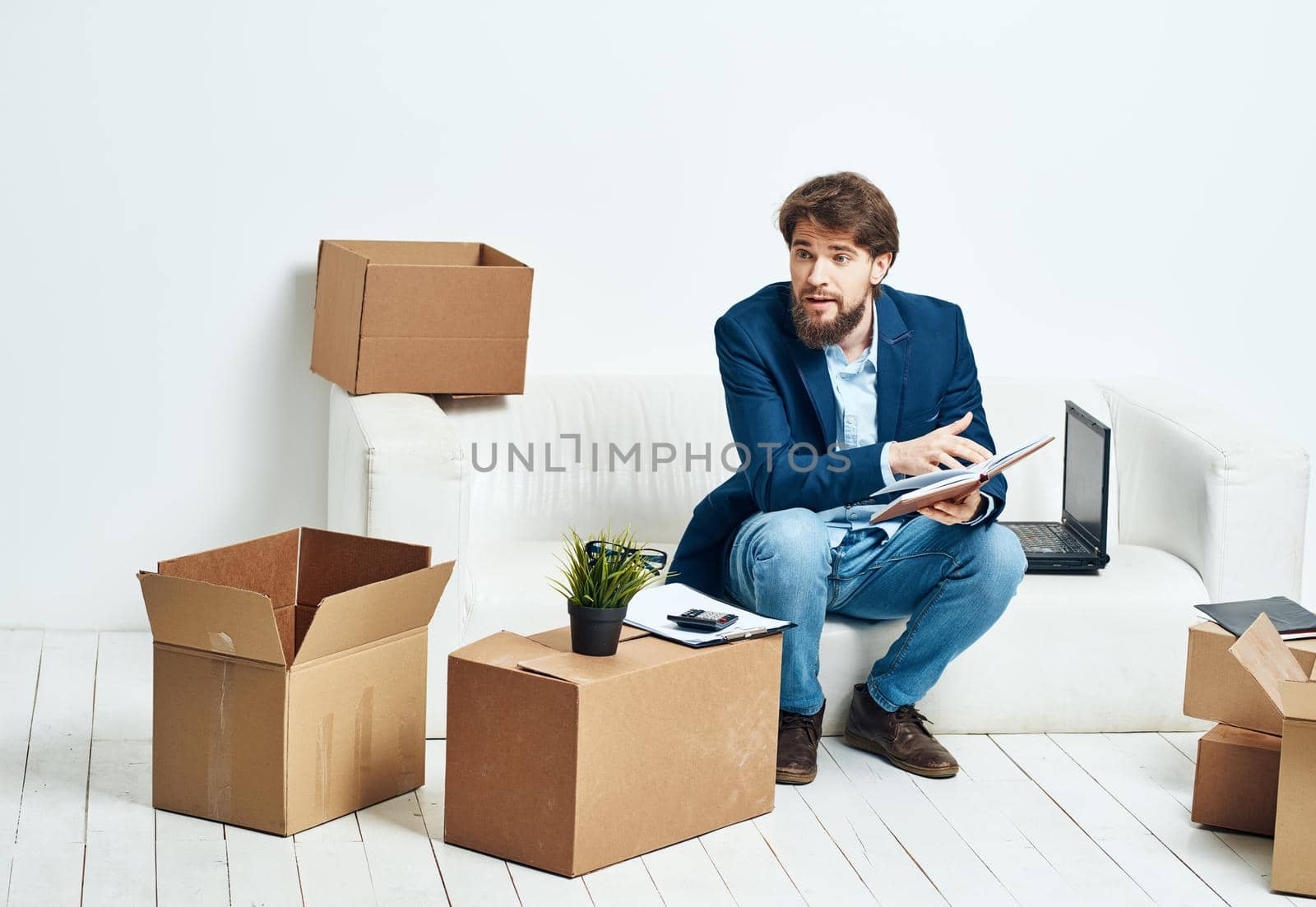 Business man sitting on the couch with laptop boxes with things unpacking . High quality photo