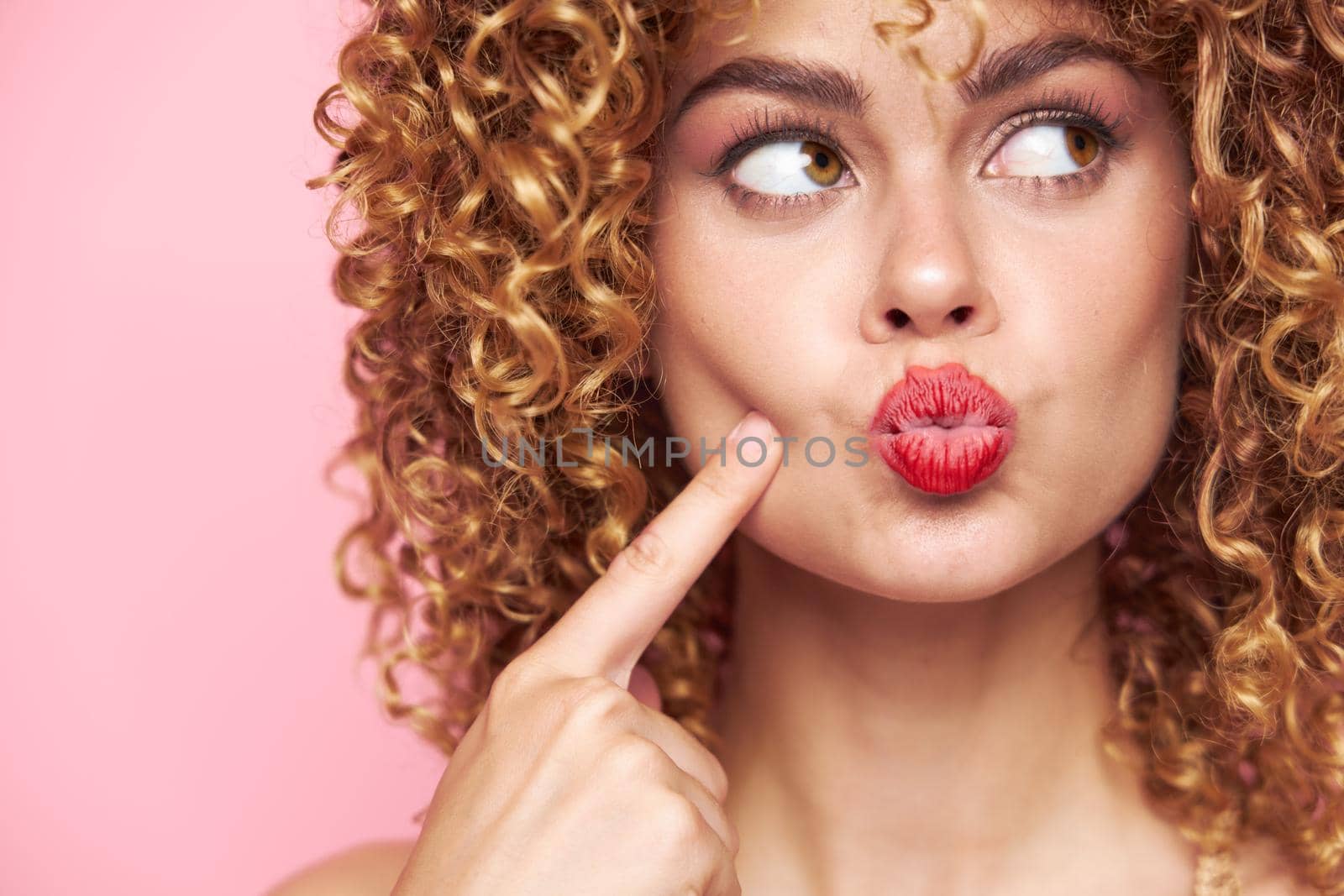 Lady curly hair red lips a look towards a grimace bright makeup close-up