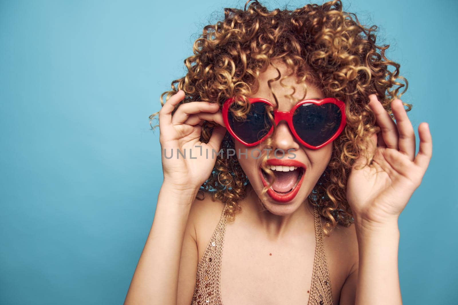 Woman open mouth sunglasses curls studio emotions lipstick blue isolated background