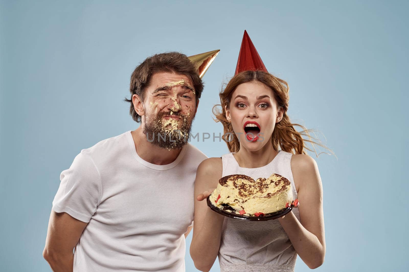 Young couple holiday fun birthday cake blue background. High quality photo