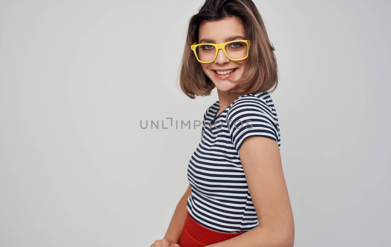 fashionable woman in glasses and in a striped t-shirt on a light background red skirt. High quality photo