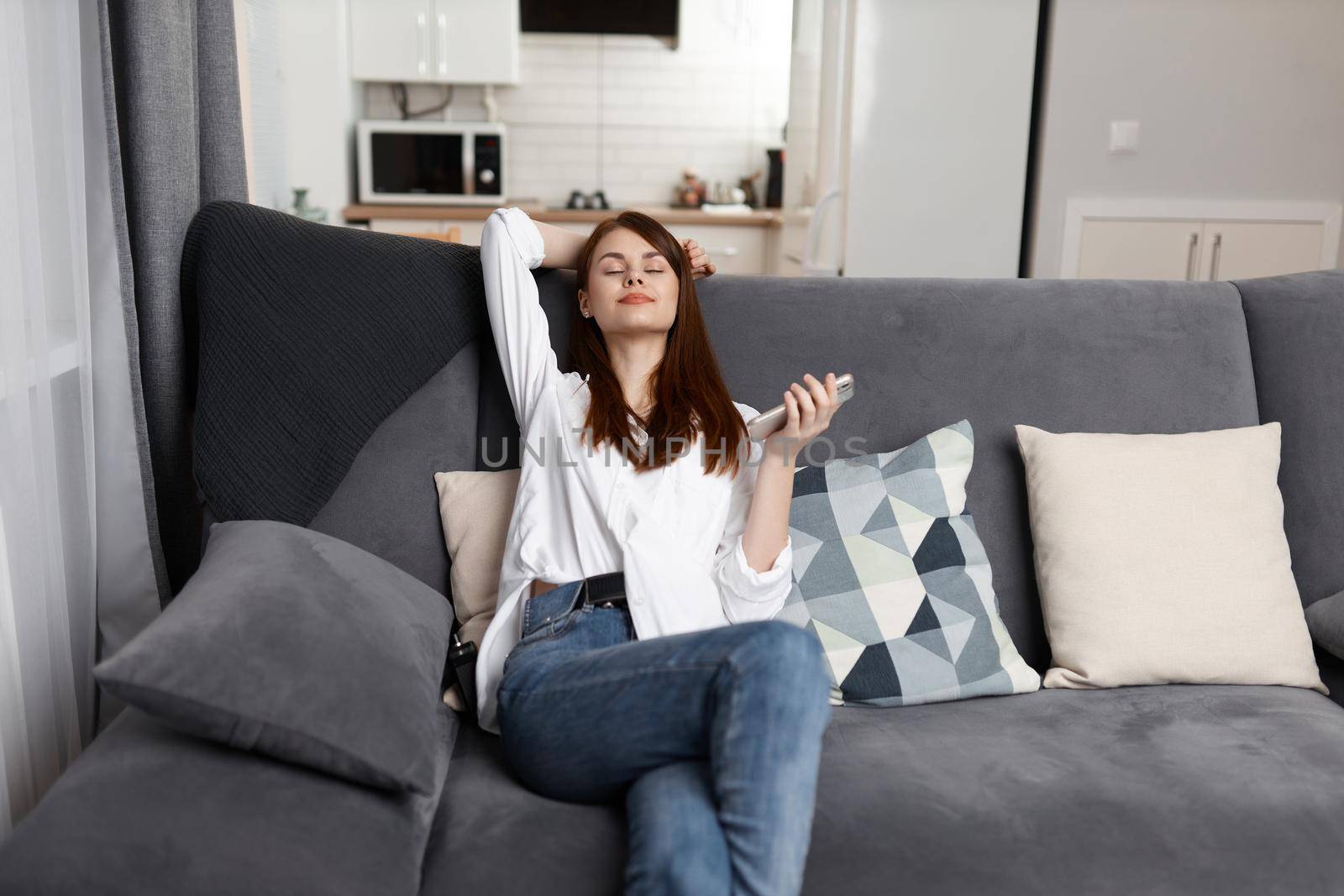 woman with closed eyes Resting at home on a comfortable sofa with a phone in her hands. High quality photo