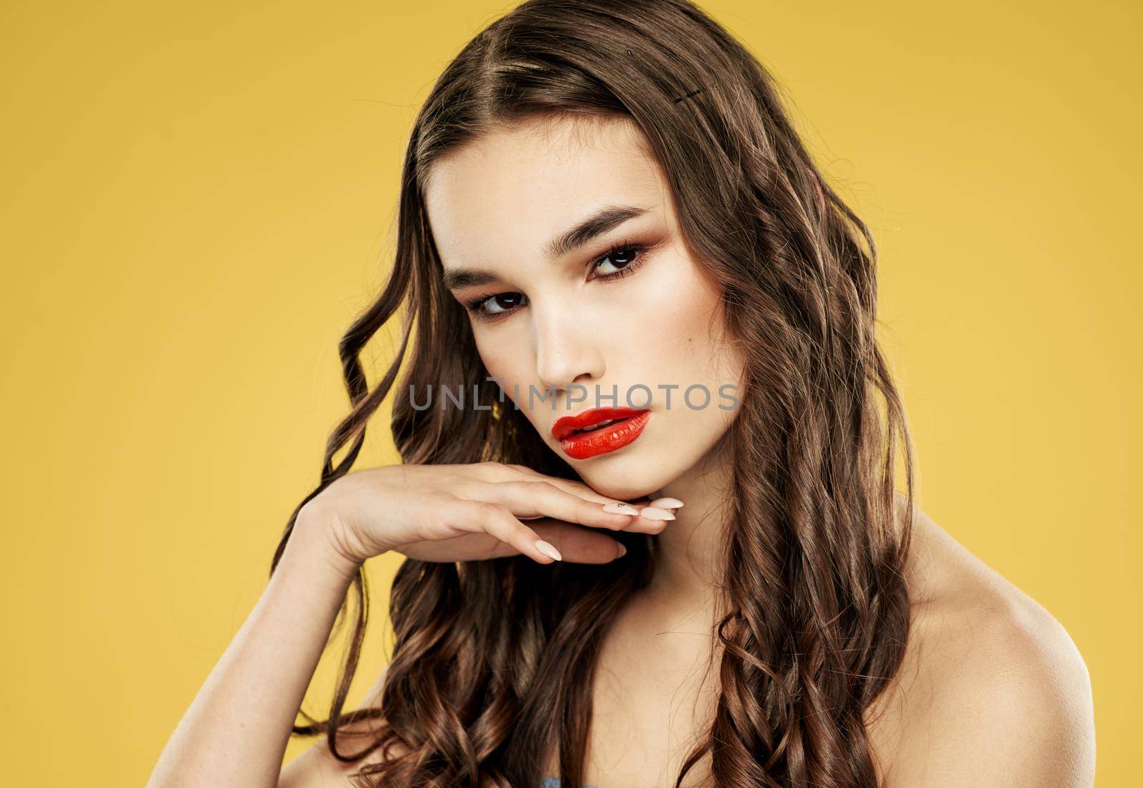 Brunette woman with red lips on a yellow background and makeup with eyeshadow. High quality photo