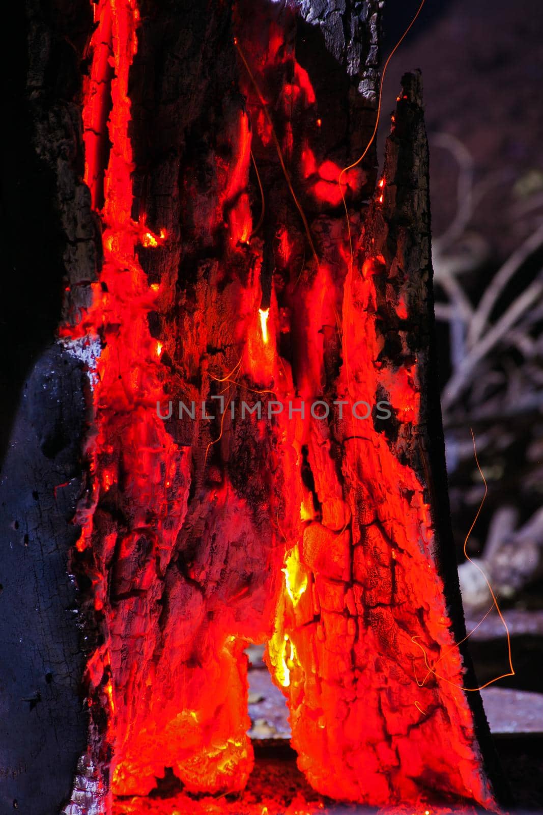 An eerie image of a smouldering tree trunk photographed at night