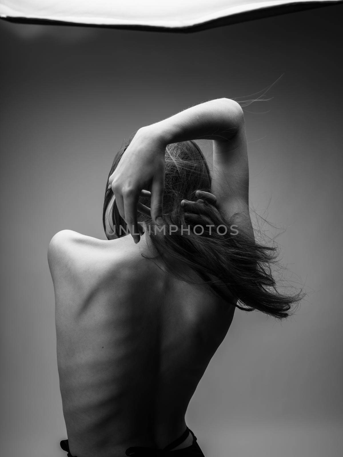 Back view of nude woman with loose hair in black and white photograph by SHOTPRIME