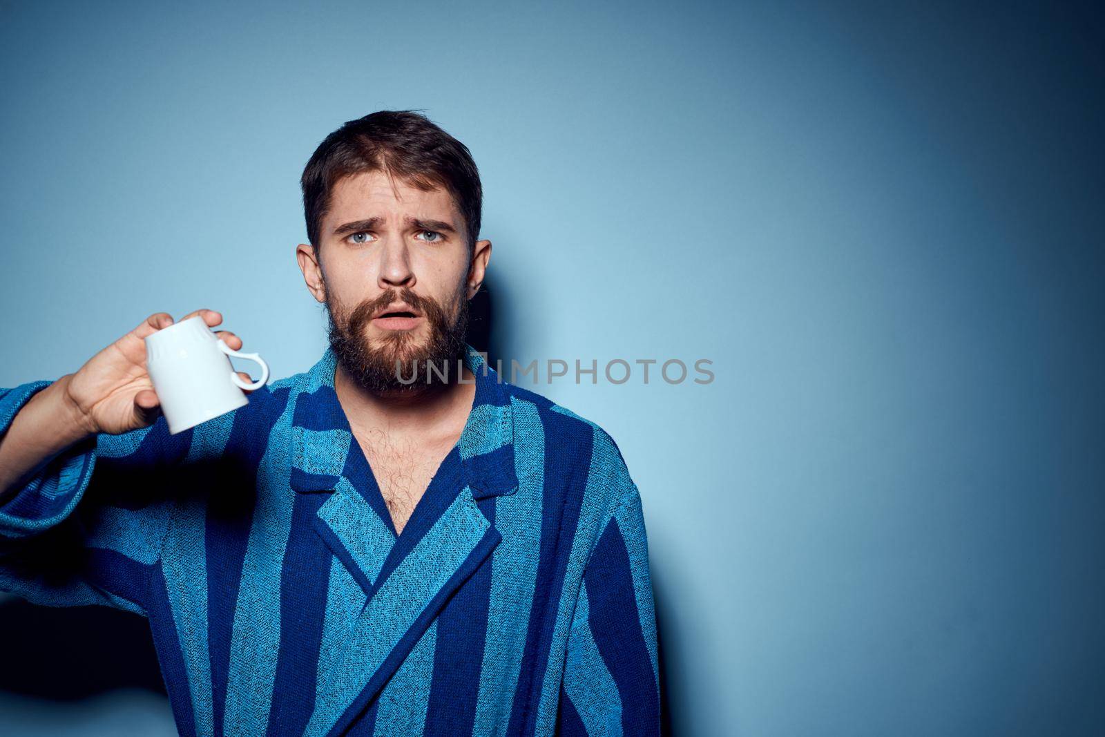 emotional man in pajamas morning lifestyle drink blue background. High quality photo