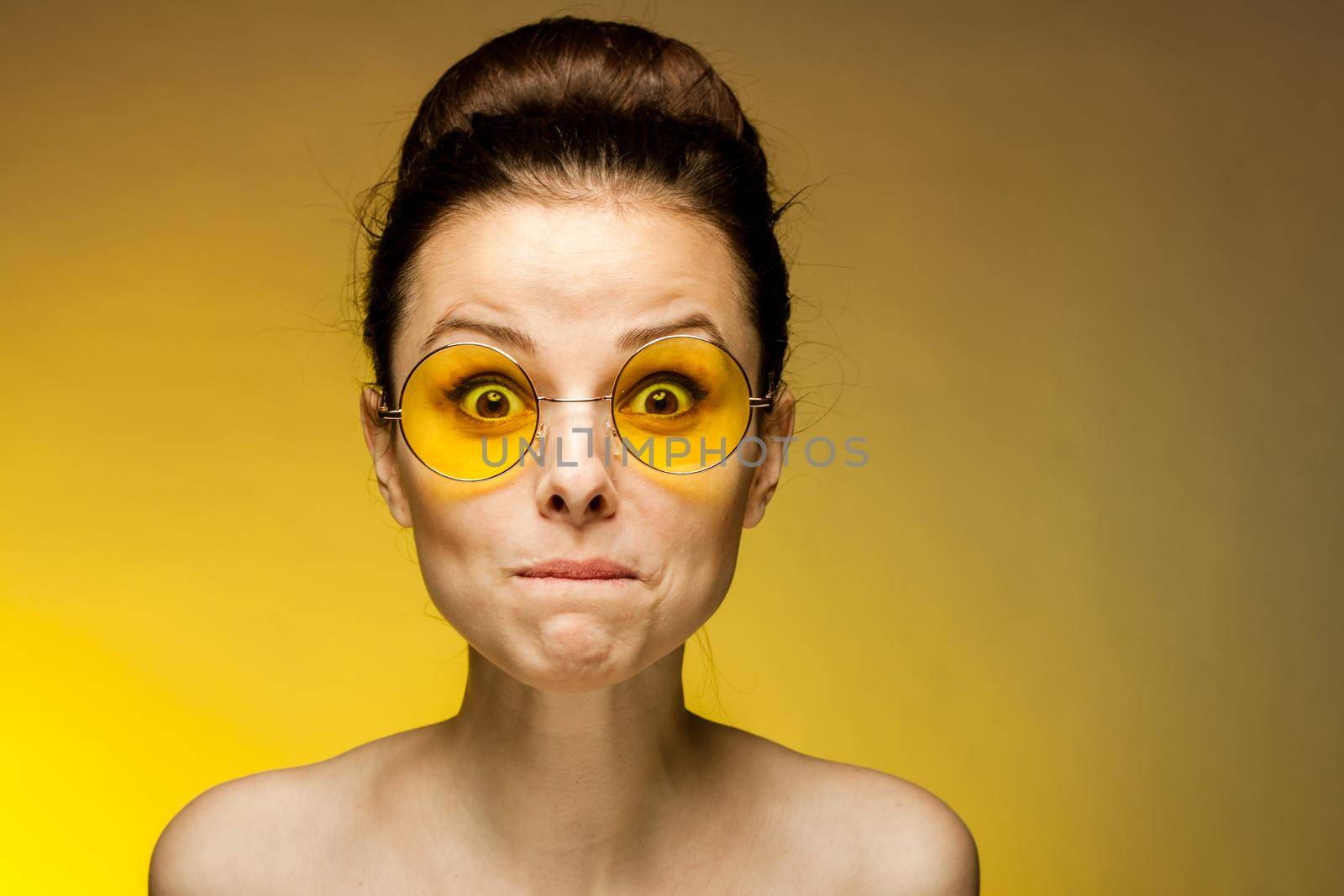 cheerful brunette naked shoulders yellow glasses emotions studio. High quality photo