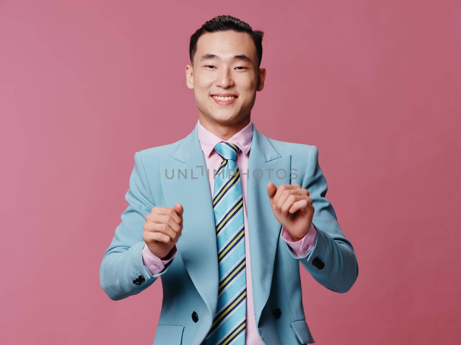 Cheerful man in blue business suit pink background . High quality photo