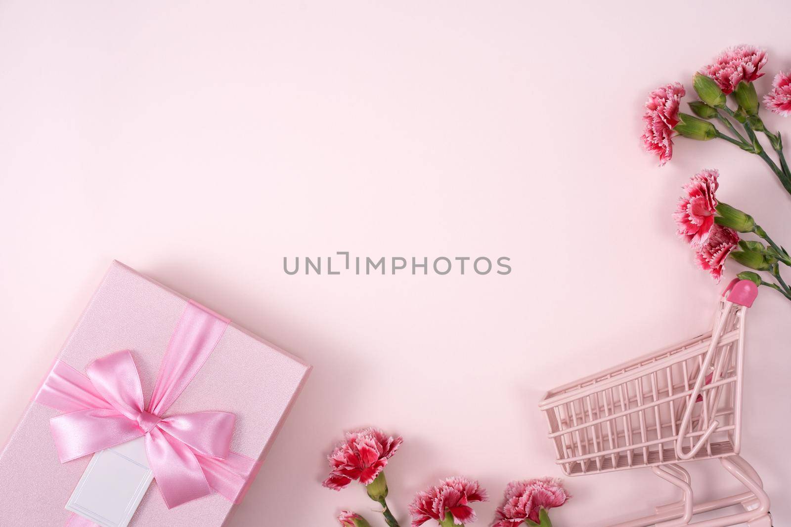 Concept of Mother's day holiday greeting design with carnation bouquet and gift on pink background