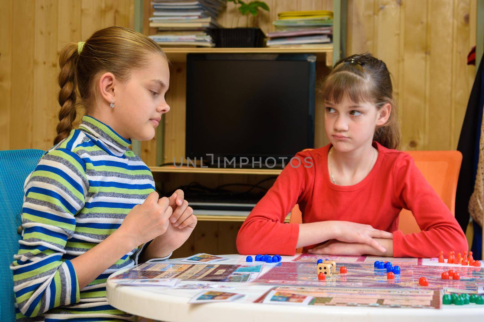 A girl is waiting for another girl to make another move while playing board games