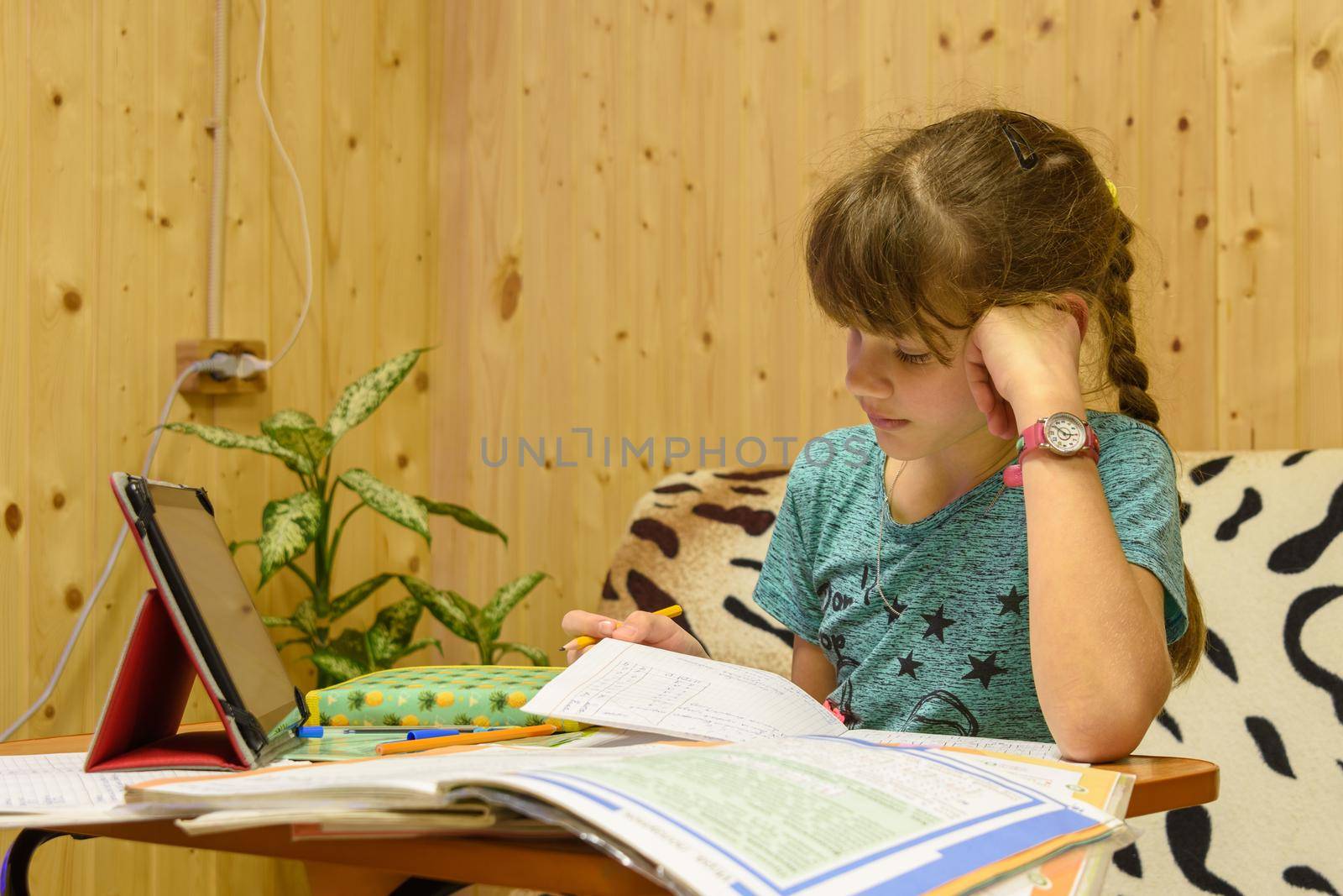 Girl teaches lessons at the table at home