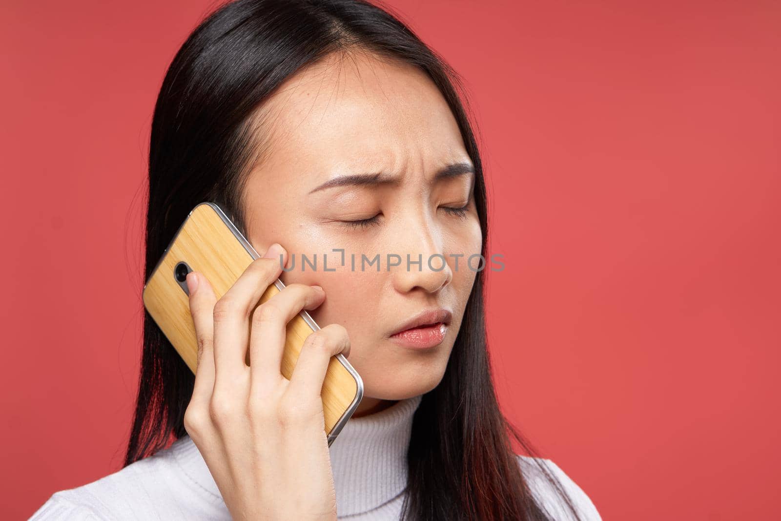 woman asian appearance talking on the phone lifestyle technology red background. High quality photo