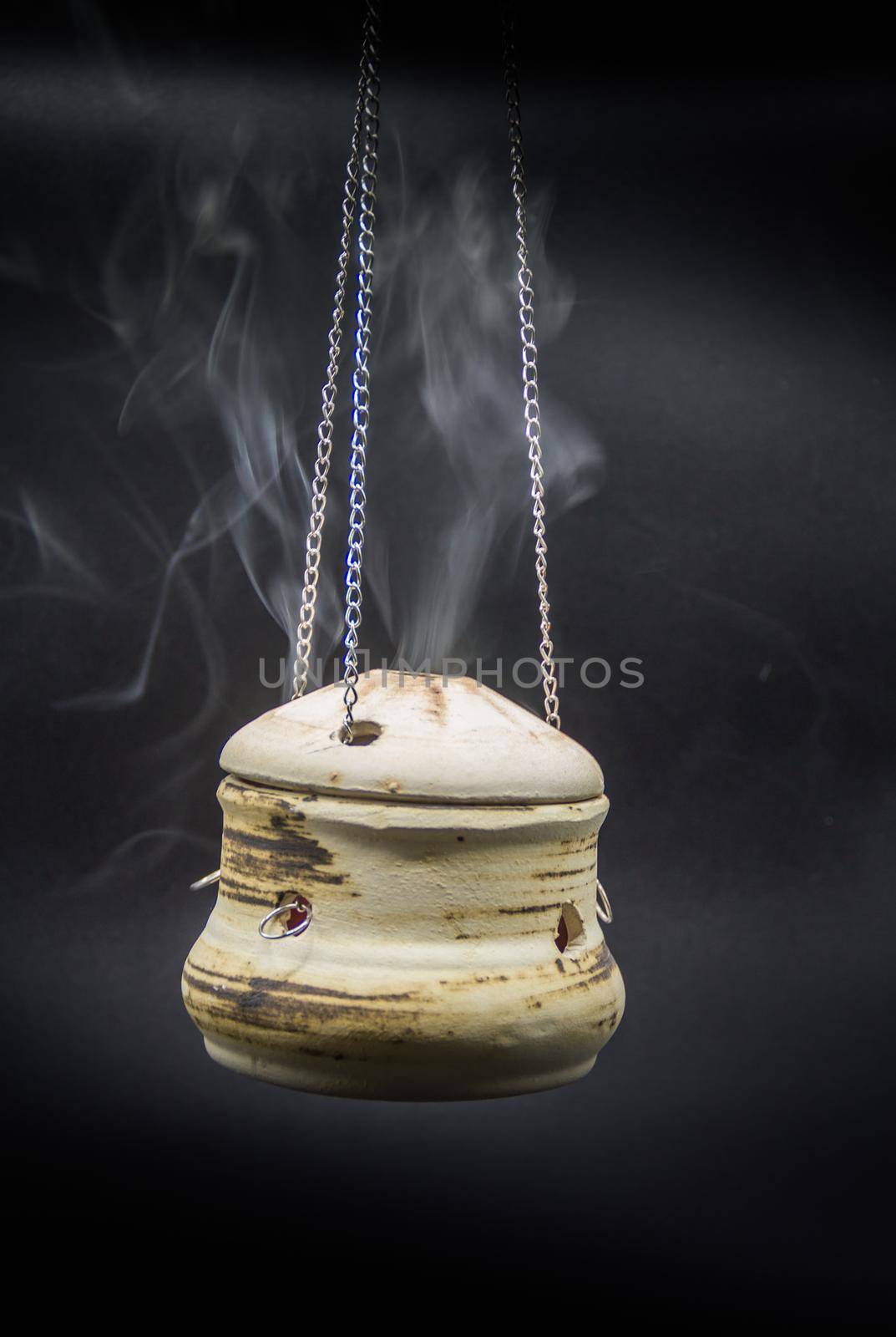 bowl of incense hanging smoke on black background