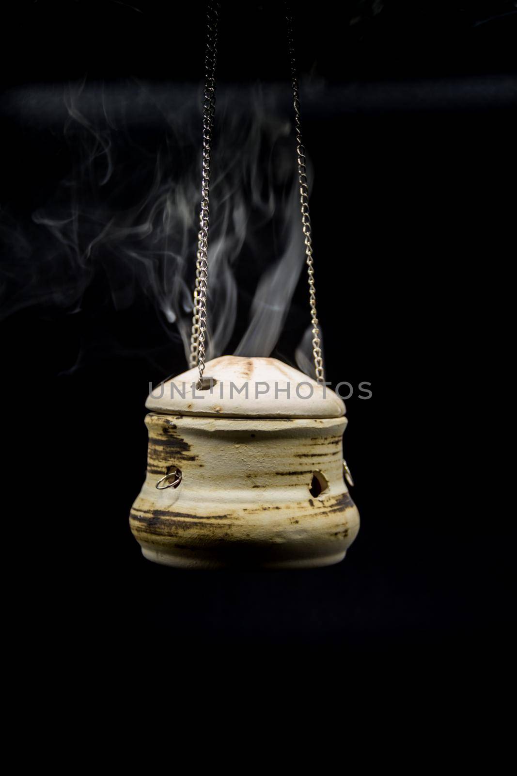 bowl of incense hanging smoke on black background