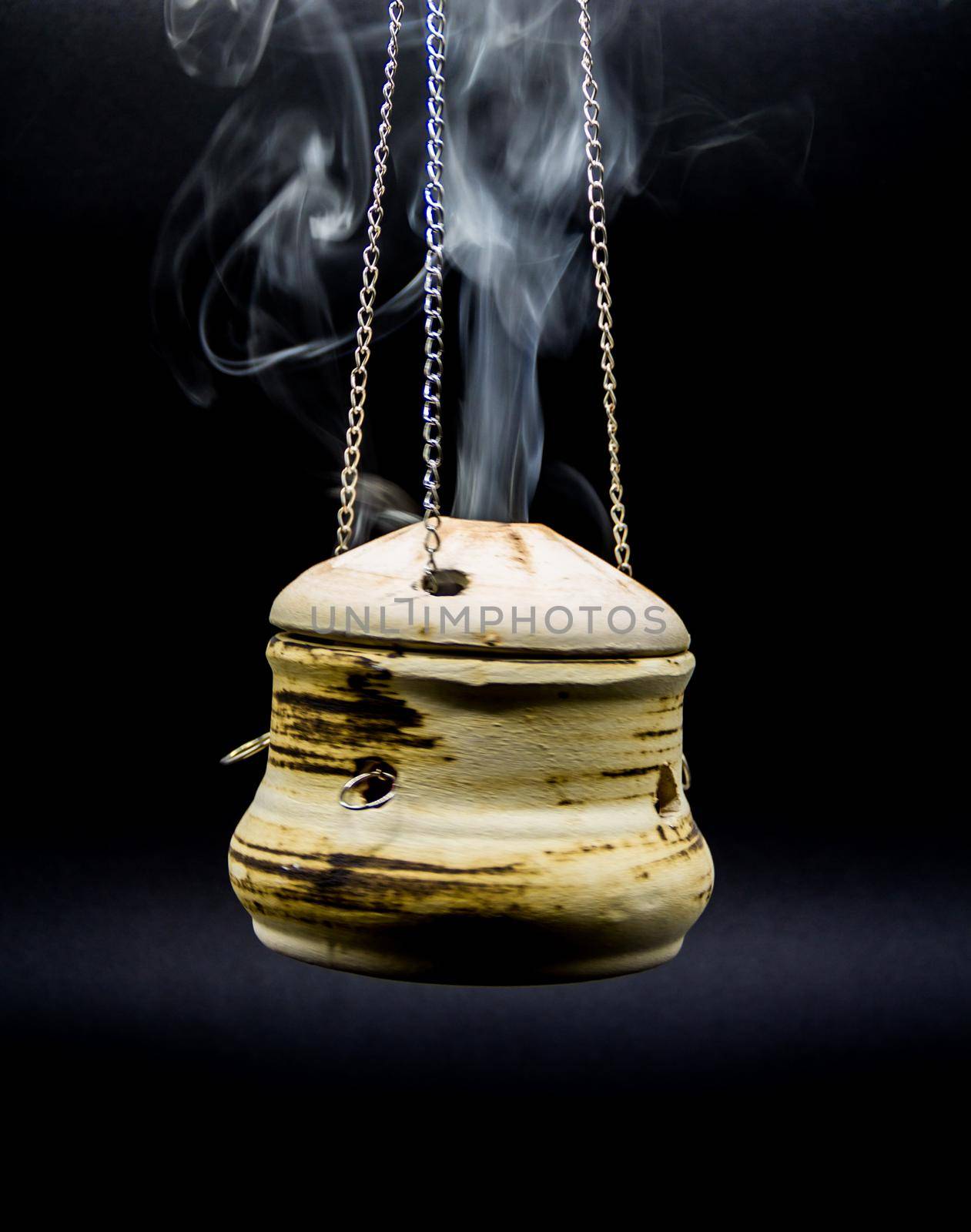 bowl of incense hanging smoke on black background