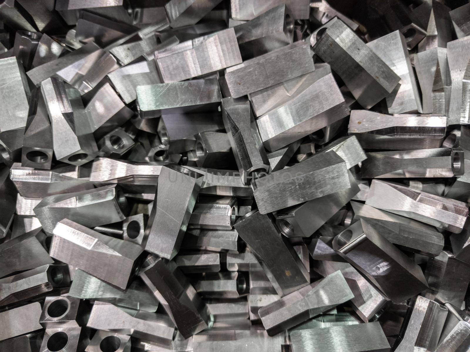 full frame industrial background of pile of shiny steel flat grinded parts - close-up with selective focus