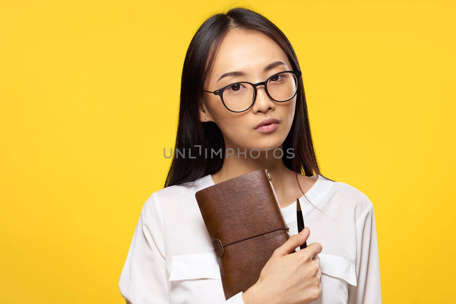 woman of asian appearance with notepad in hands and pen glasses elegant style work. High quality photo
