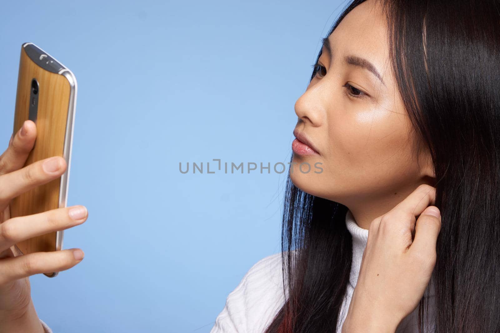 woman asian appearance phone in hand communicating internet blue background. High quality photo