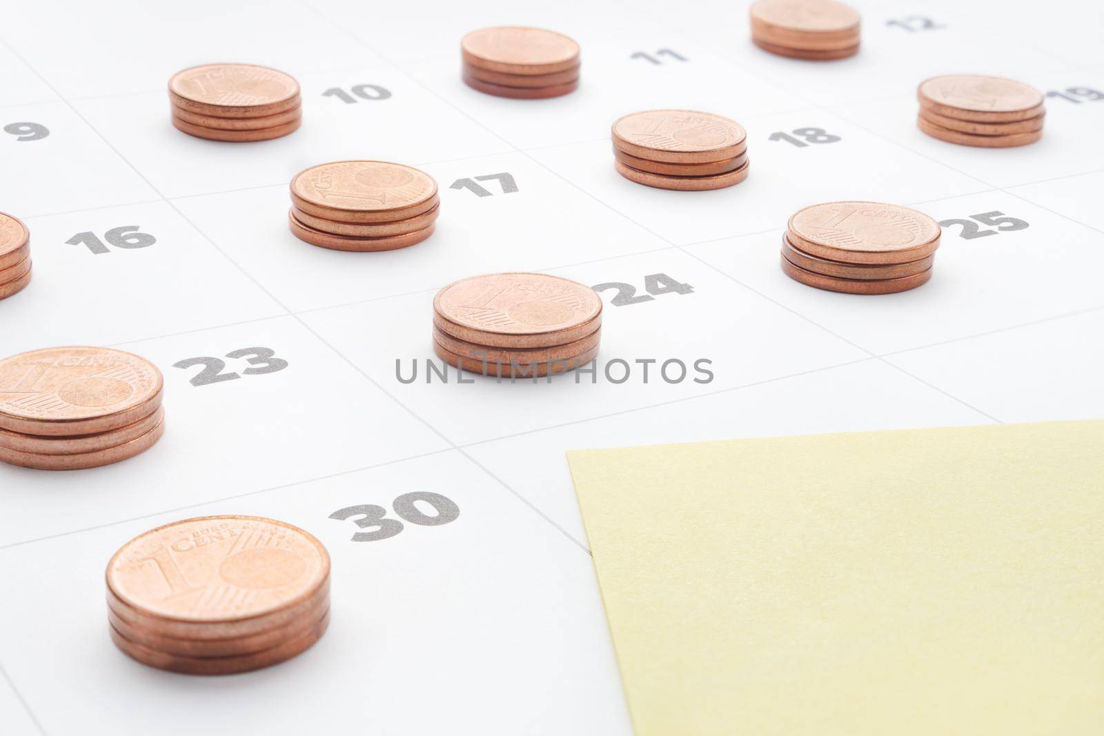 Plan save money to budget management. Cost of living. Monthly report. Empty yellow paper note in last day of month calendar with stacks euro coins. Time is money stack of coins on daily calendar pages by synel