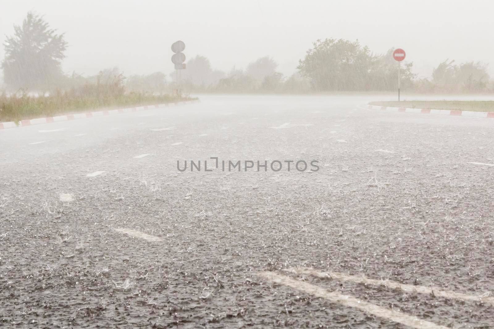 Heavy rain with hail is falling along the highway. Large drops with lumps of snow