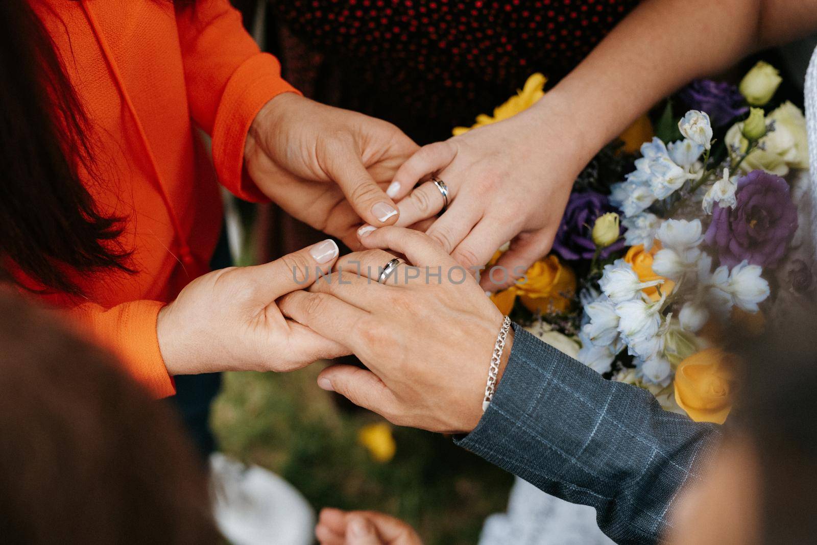 the bride and groom tenderly hold hands between them love and relationships by Andreua