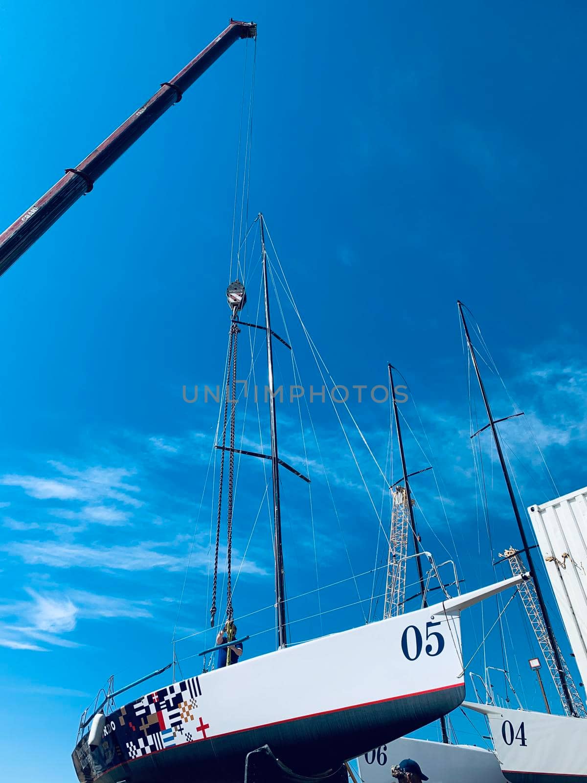 Russia, St.Petersburg, 26 May 2020: Port Hercules, the big industrial crane lifts the sailboat and floats it, the beginning of a season of sailing, a skyscraper on a background, sailboat is groundless, sunny weather
