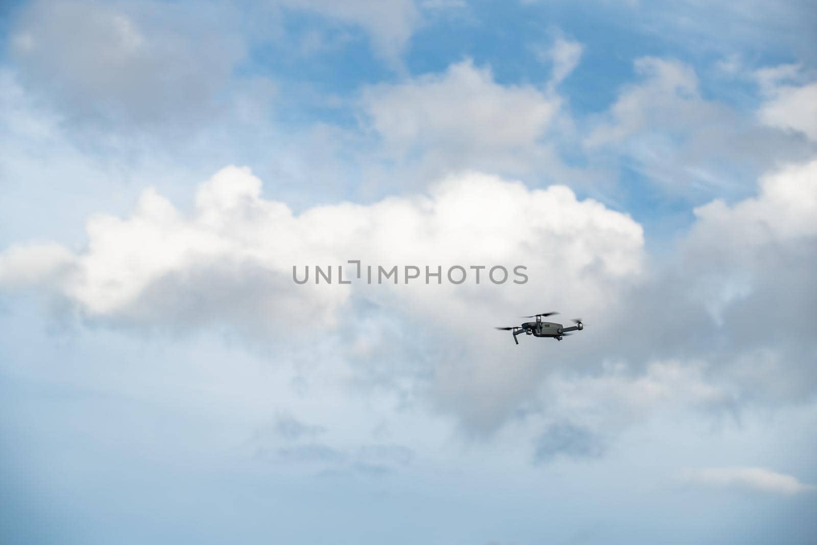 The flying soaring drone in the sky, the blue sky with white clouds, sunny weather, Turning propellers, nobody. High quality photo