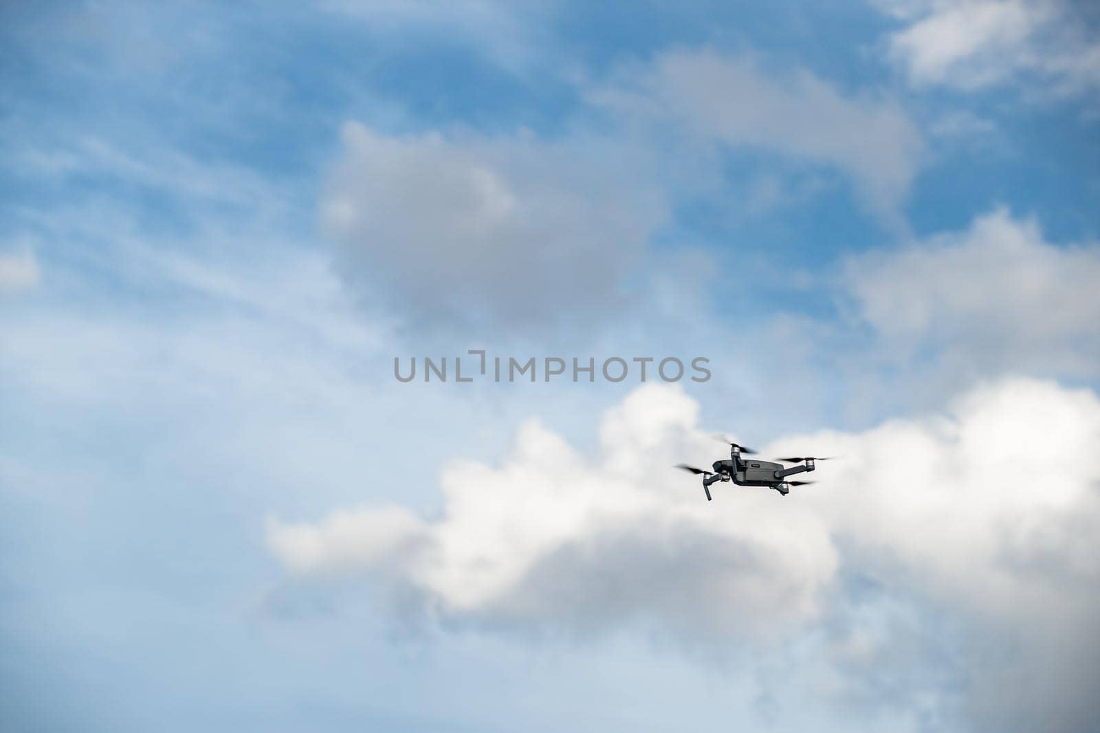 The flying soaring drone in the sky, the blue sky with white clouds, sunny weather, Turning propellers, nobody by vladimirdrozdin