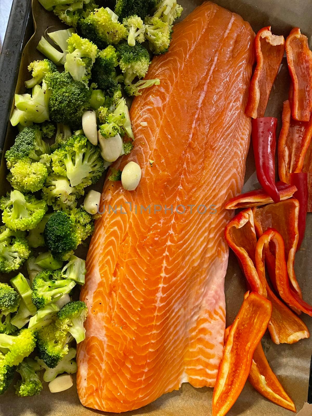 A large piece of red fish fillet lies on the prostena, vegetables ready to be locked, broccoli, red sweet pepper by vladimirdrozdin