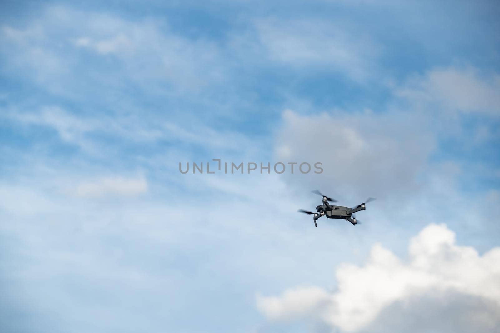 The flying soaring drone in the sky, the blue sky with white clouds, sunny weather, Turning propellers, nobody by vladimirdrozdin