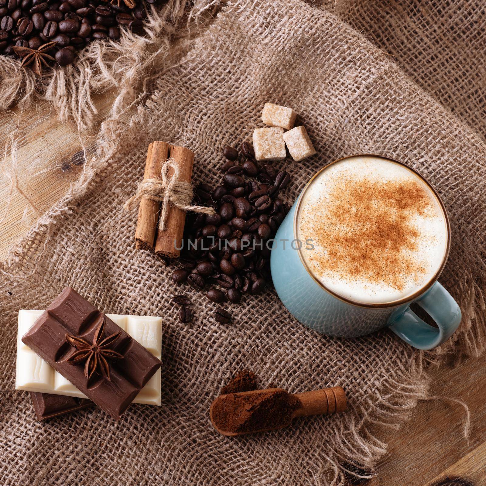 cup of coffee with cinnamon, anise chocolate on wooden background view above