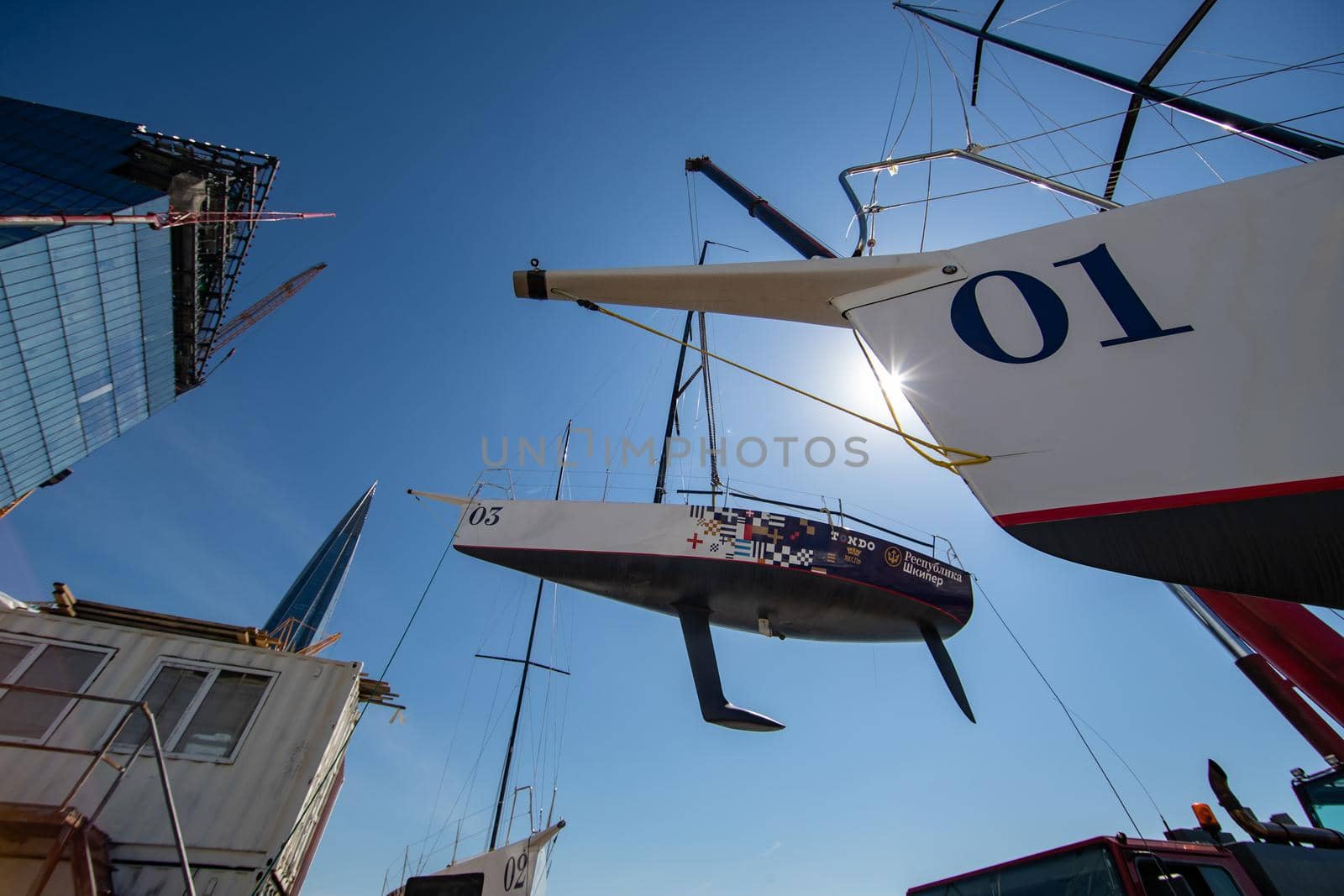 Russia, St.Petersburg, 26 May 2020: Port Hercules, the big industrial crane lifts the sailboat and floats it, the beginning of a season of sailing, a skyscraper on a background, sailboat is groundless by vladimirdrozdin