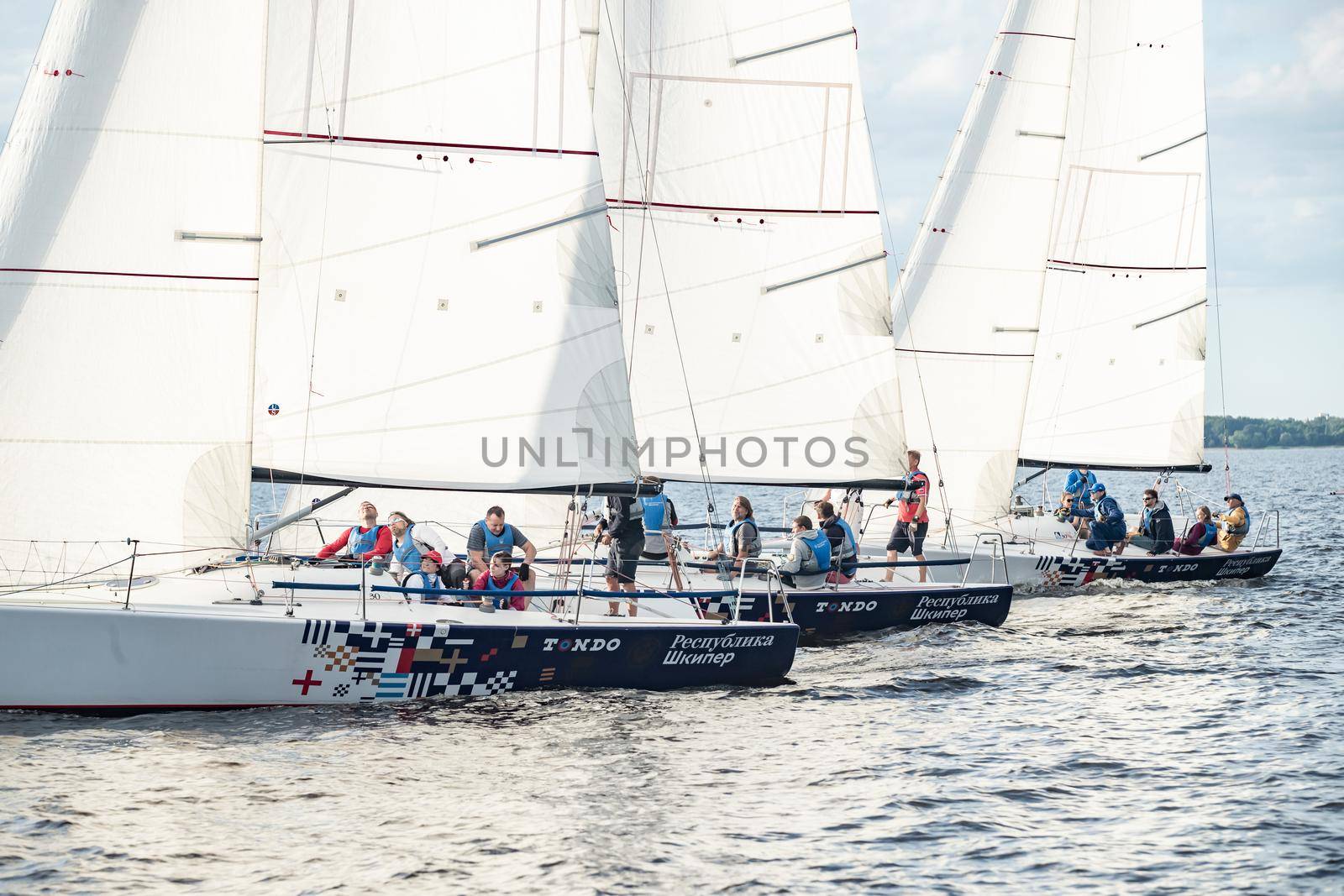 Russia, St.Petersburg, 06 July 2020: The Sail boats regatta at Neva river at sunny day, start of race, fun, passion, Sun patches of light on water, sail school by vladimirdrozdin