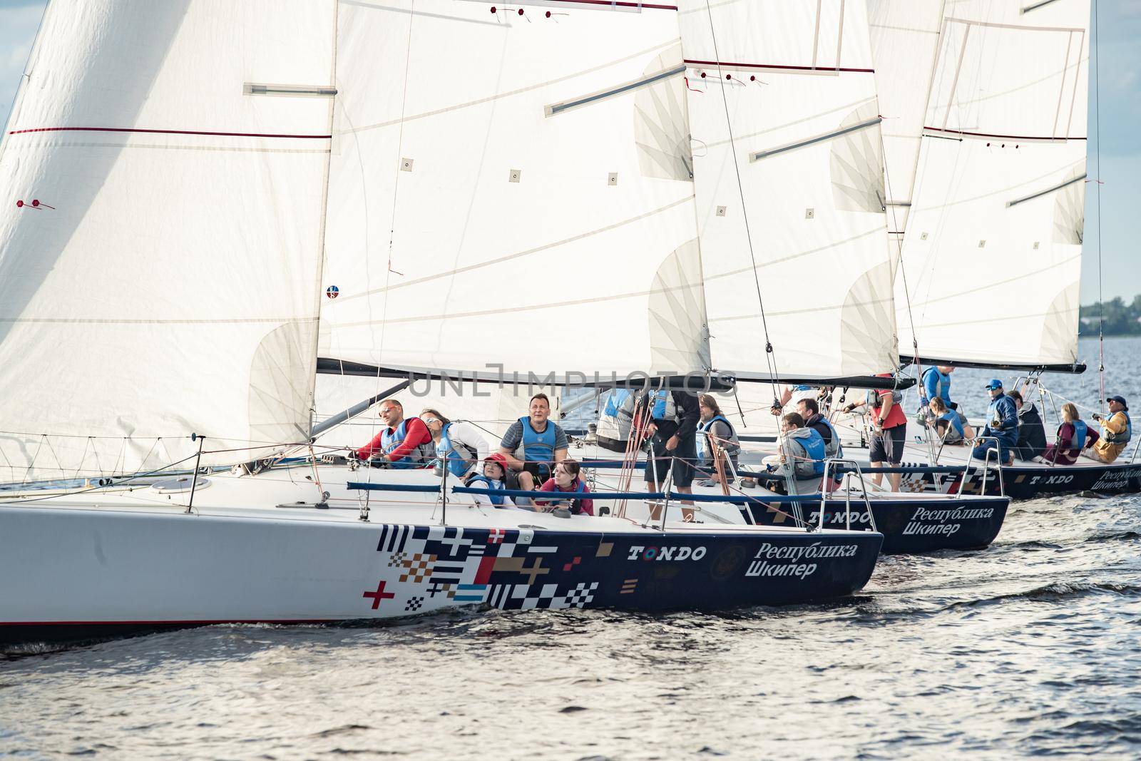 Russia, St.Petersburg, 06 July 2020: The Sail boats regatta at Neva river at sunny day, start of race, fun, passion, Sun patches of light on water, sail school by vladimirdrozdin