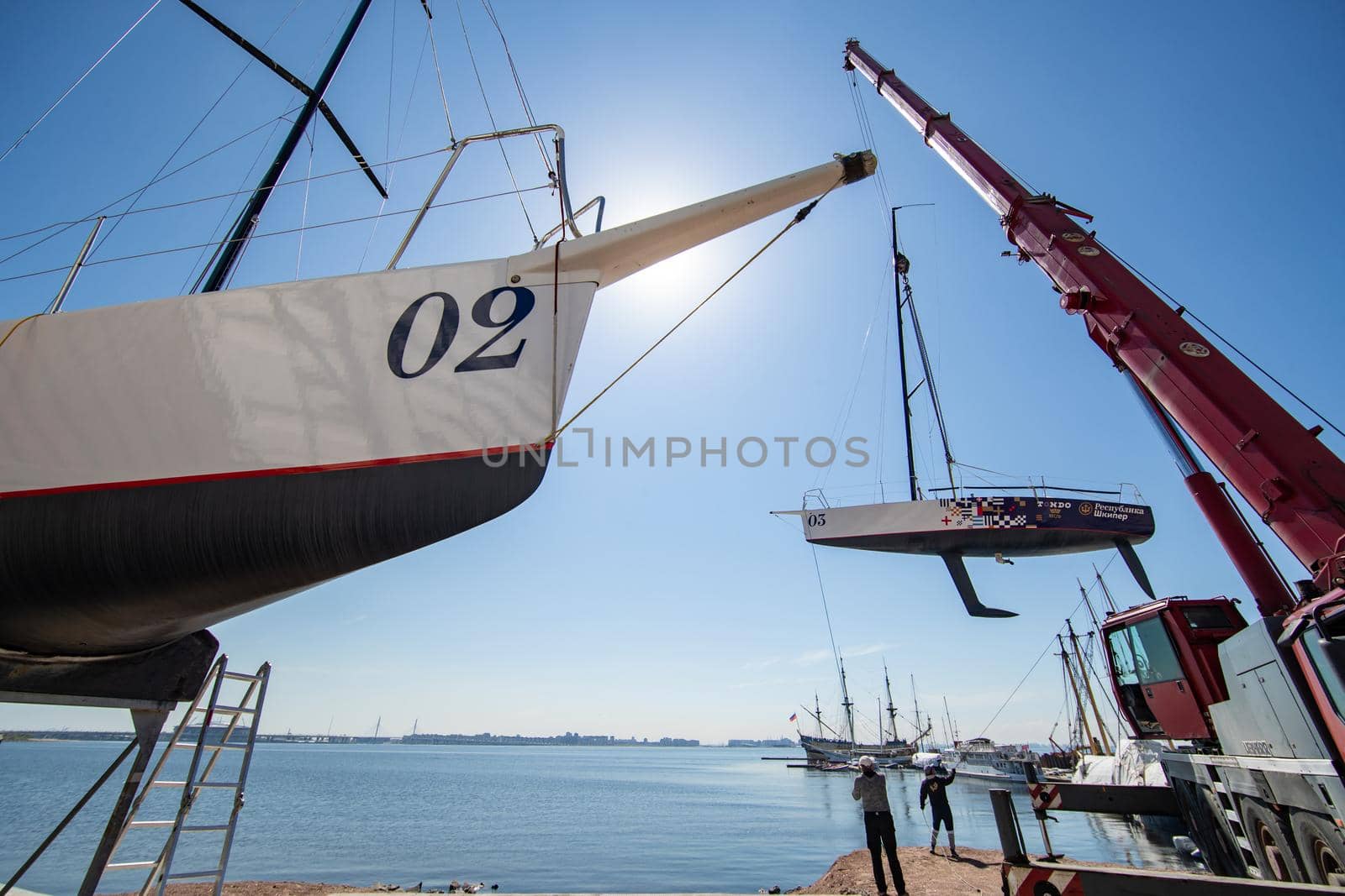 Russia, St.Petersburg, 26 May 2020: Port Hercules, the big industrial crane lifts the sailboat and floats it, the beginning of a season of sailing, a skyscraper on a background, sailboat is groundless by vladimirdrozdin