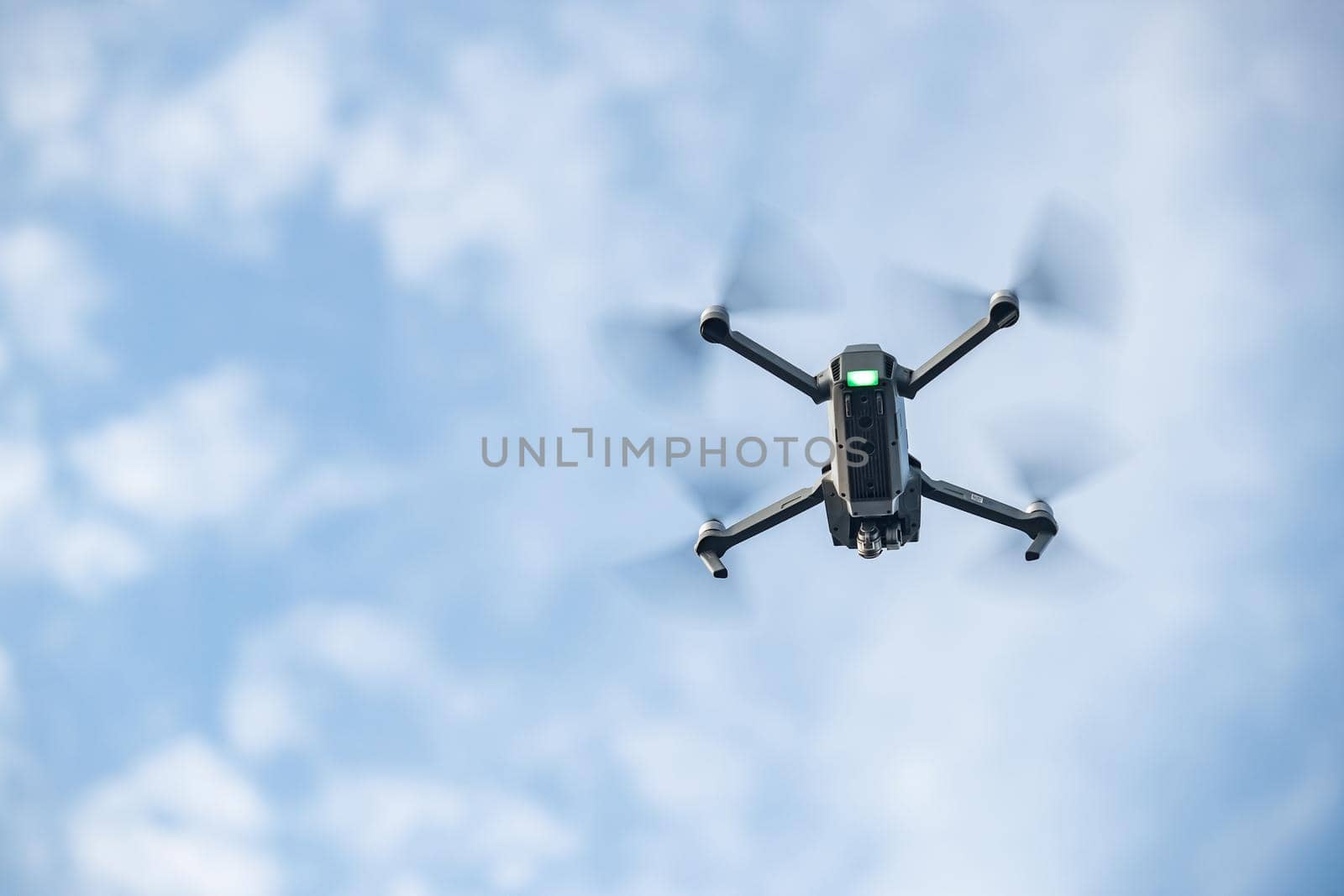 The flying soaring drone in the sky, the blue sky with white clouds, sunny weather, Turning propellers, nobody. High quality photo