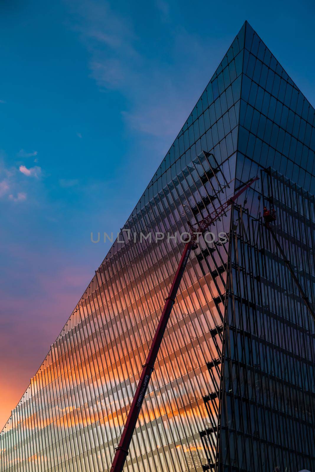 Russia, St.Petersburg, 03 July 2020: The color image of skyscraper Lakhta center at sunset, Reflection of the sunset sky in a glass facade of the building, It is the highest skyscraper in Europe, Completion of construction, Huge construction crane