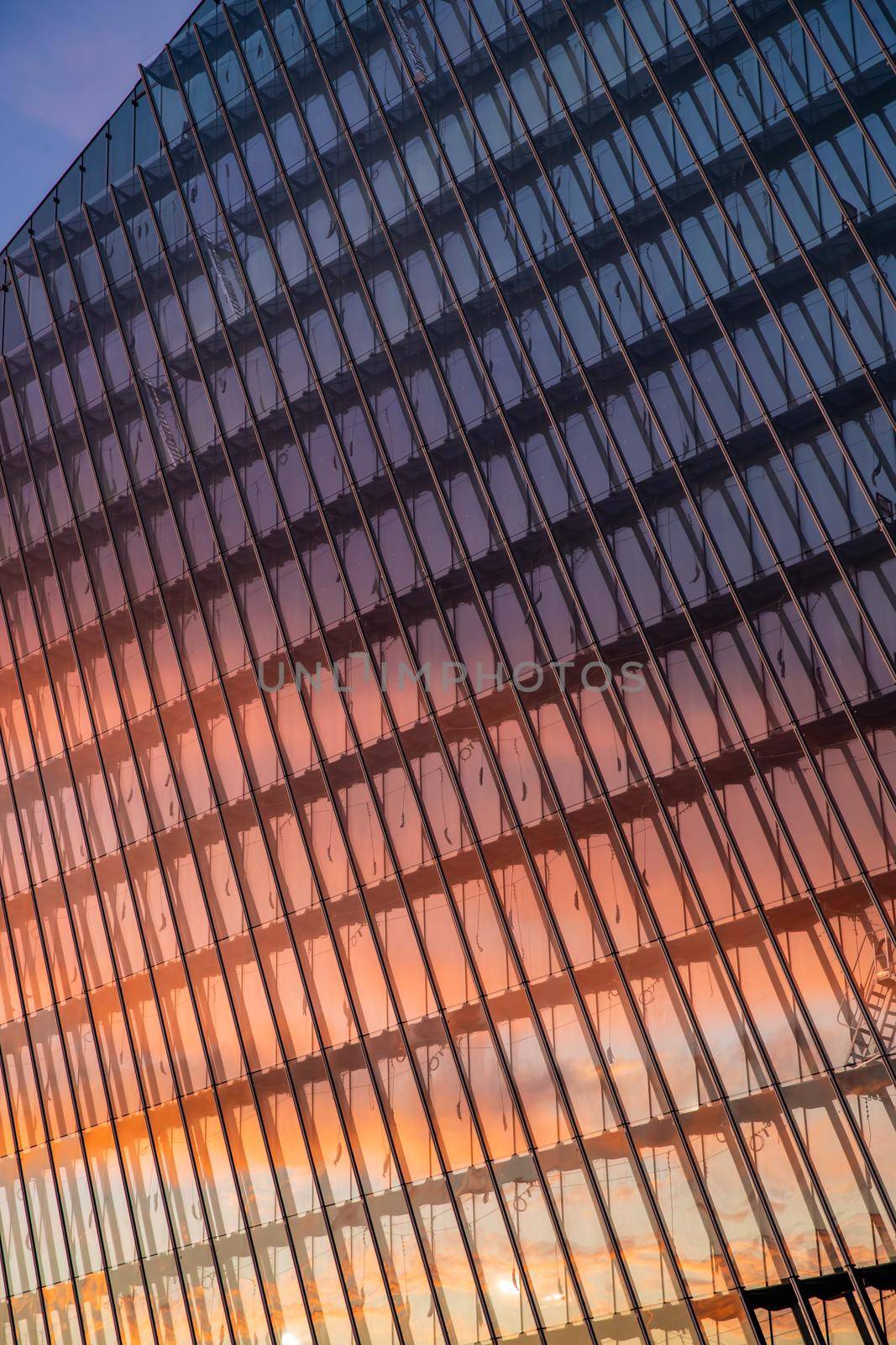 Reflection of the sunset sky in a glass facade of the building, skyscraper at sunset