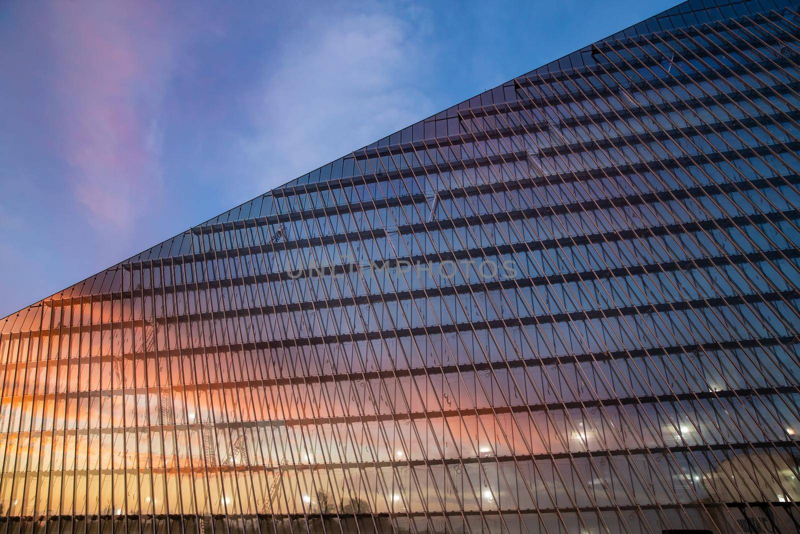 Reflection of the sunset sky in a glass facade of the building, skyscraper at sunset