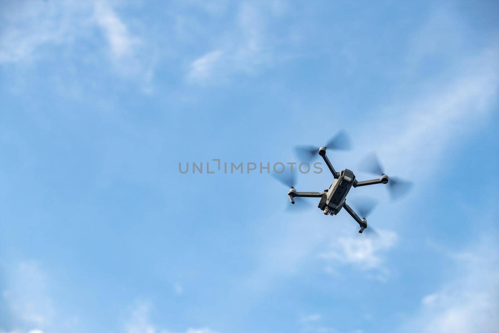 The flying soaring drone in the sky, the blue sky with white clouds, sunny weather, Turning propellers, nobody. High quality photo